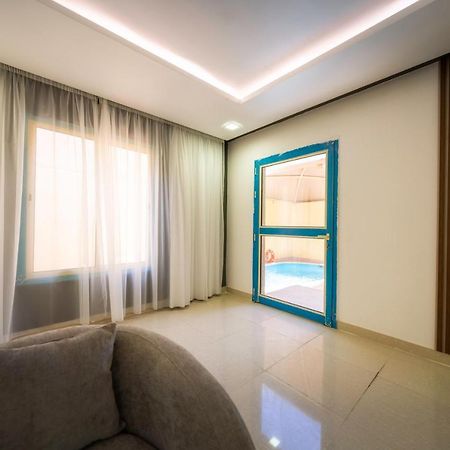 Mirada Gold Jizan - Resort & Private Pools Eksteriør billede The photo shows a modern interior space that appears to be a room in a home or a building. There is a large window with sheer curtains letting in natural light, which contributes to a bright and airy atmosphere. On one side of the room, there is a sl